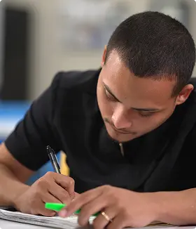 STVT male student writing in notebook